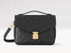 Black handbag with gold clasp on a light gray background