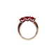 Gold ring with three red gemstones on a white background