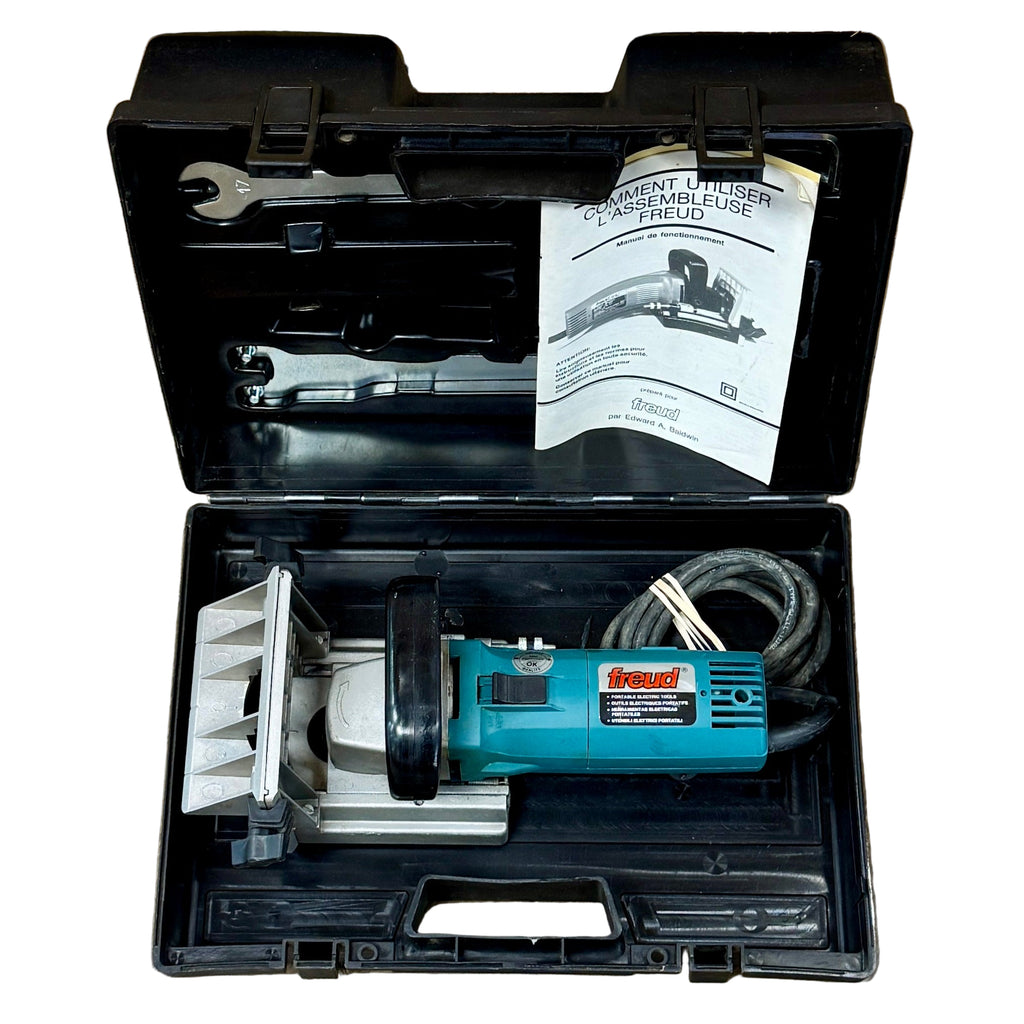 Freud 5-Amp 4" Corded Biscuit Joiner Machine w/ Hard Case (JS100) Open tool case with a blue power tool and accessories on a wooden floor.