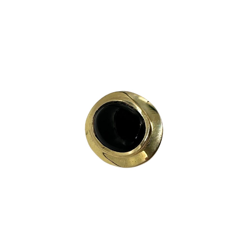 Round brass object with a black center on a white background