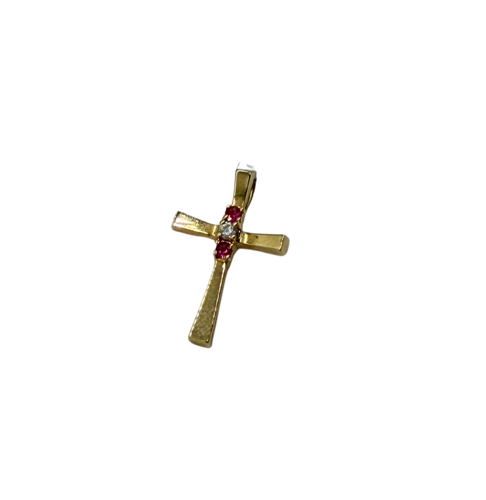 Gold cross pendant with red gemstone and clear stone on a white background