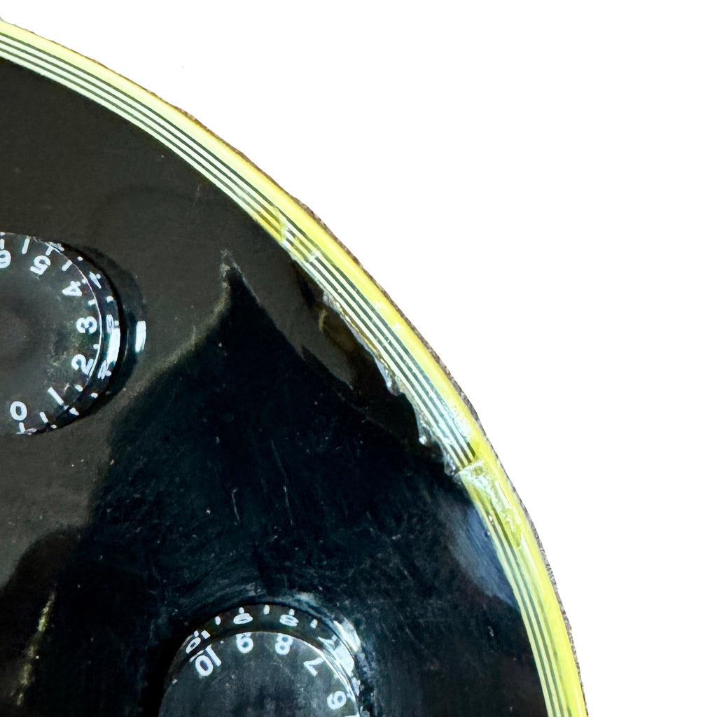 Gibson Les Paul Supreme Electric Guitar w/ Hard Case Close-up of a black and yellow object with circular components on a textured surface