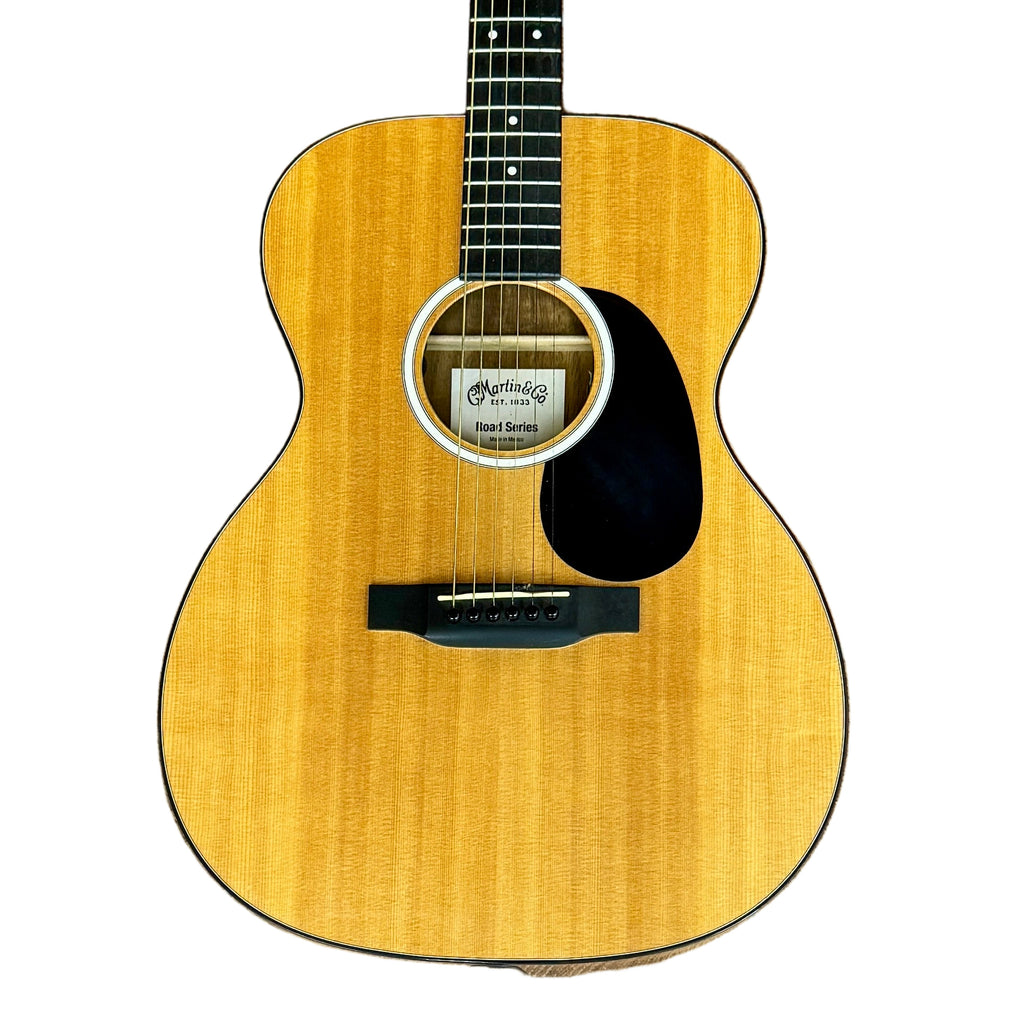 Martin Road Series 000-12E Acoustic-Electric Guitar w/ Soft Case Acoustic guitar leaning against a wooden paneled wall