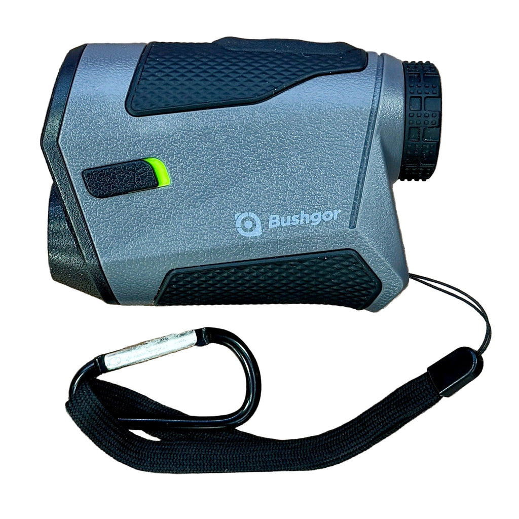 Bushgor K600G Laser Golf Rangefinder w/ Slope Rangefinder with carrying strap on a wooden surface, featuring the Bushbox brand.