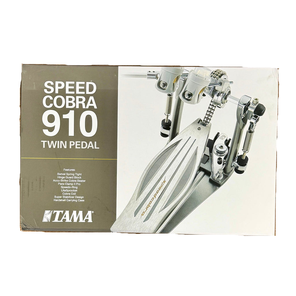 TAMA Speed Cobra 910 Twin Double Bass Drum Pedal w/ Hard Case TAMA Speed Cobra 910 Twin Pedal packaging on a wooden floor with shoes at the bottom.