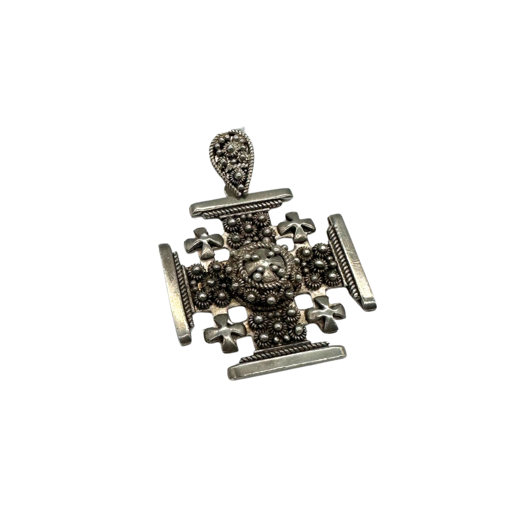 Silver cross pendant with intricate designs on a white background