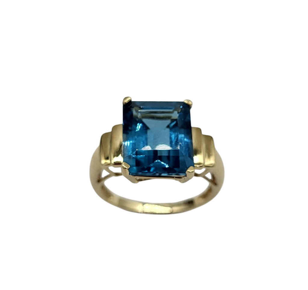 Gold ring with a blue gemstone on a white background