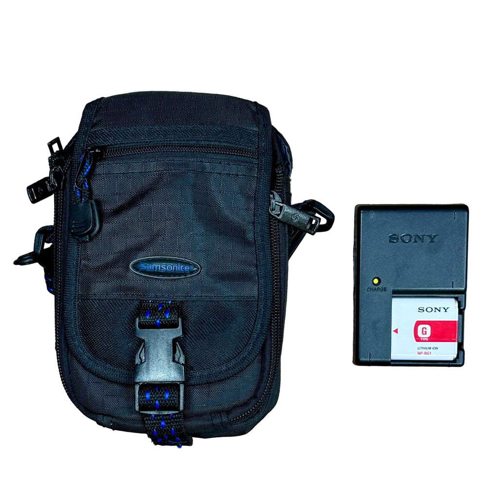 Sony Cyber-Shot DSC-H55 14.1MP Digital Camera w/ Case - Black Samsonite bag with a Sony battery and memory card on a wooden surface