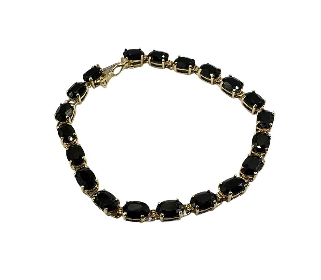 Bracelet with black gemstones and gold accents on a white background