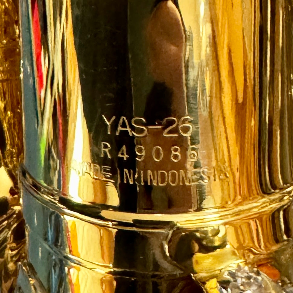 Yamaha YAS-26 Eb Alto Saxophone w/ Hard Case (Serial # R49086) Close-up of a gold and silver object with 'YAS-26' and 'R49085' engraved on it.