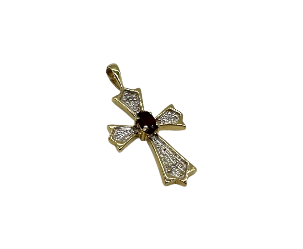 Gold cross pendant with a red gemstone on a black background