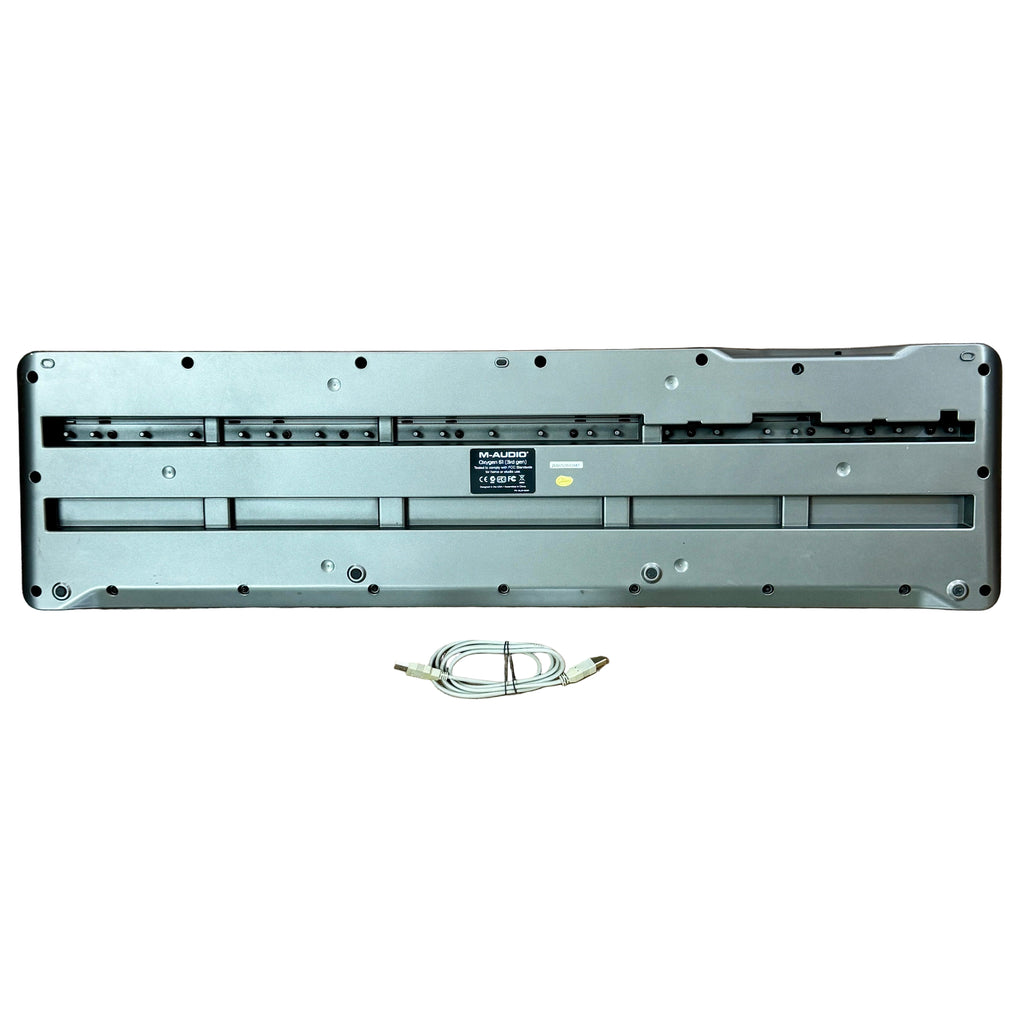 M-AUDIO Oxygen 61 61-Key USB MIDI Keyboard Controller - 3rd Generation Metallic keyboard baseplate with a cable on a wooden floor