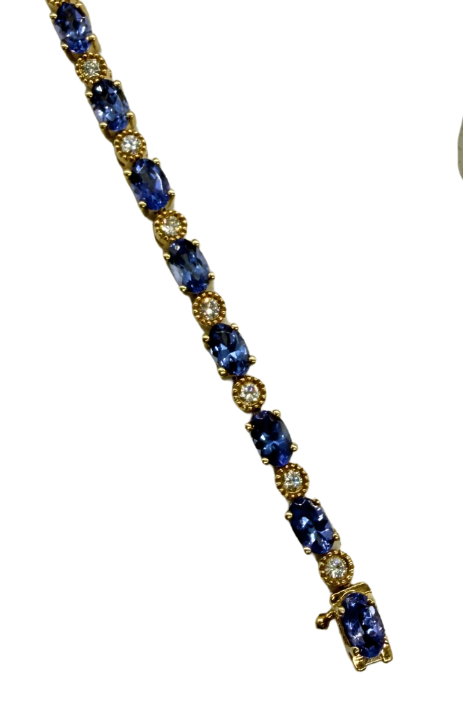 Gold bracelet with blue gemstones on a white background