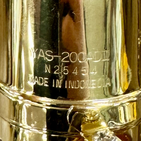 Yamaha YAS-200ADII Advantage Standard Alto Saxophone w/ Hard Case (Serial # N25454) Close-up of a metallic object with engraved text, including 'MADE IN INDONESIA'.