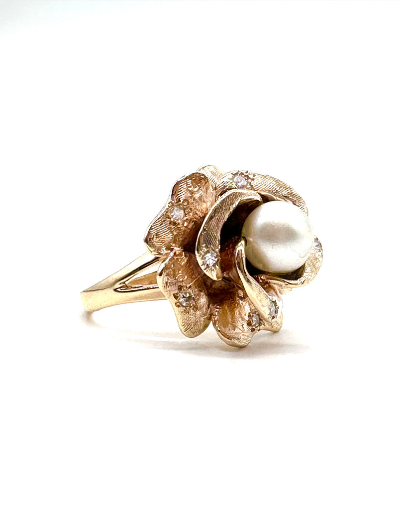 Gold ring with a pearl and floral design on a white background