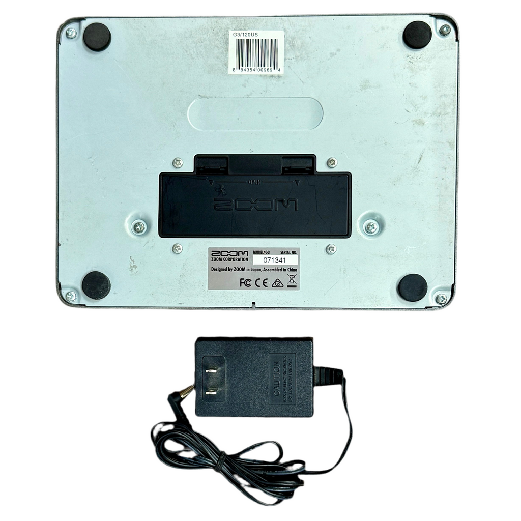 ZOOM G3 Guitar Effects & Amp Simulator Pedal Back view of a device with 'Zoom' branding and a power adapter on a white background