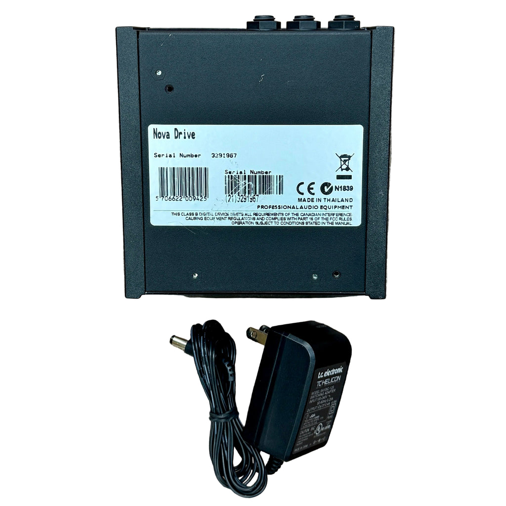 TC Electronic NDR-1 NOVA DRIVE Analog Overdrive & Distortion Guitar Effects Pedal Black electronic device with label, power adapter, and cable on a wooden surface