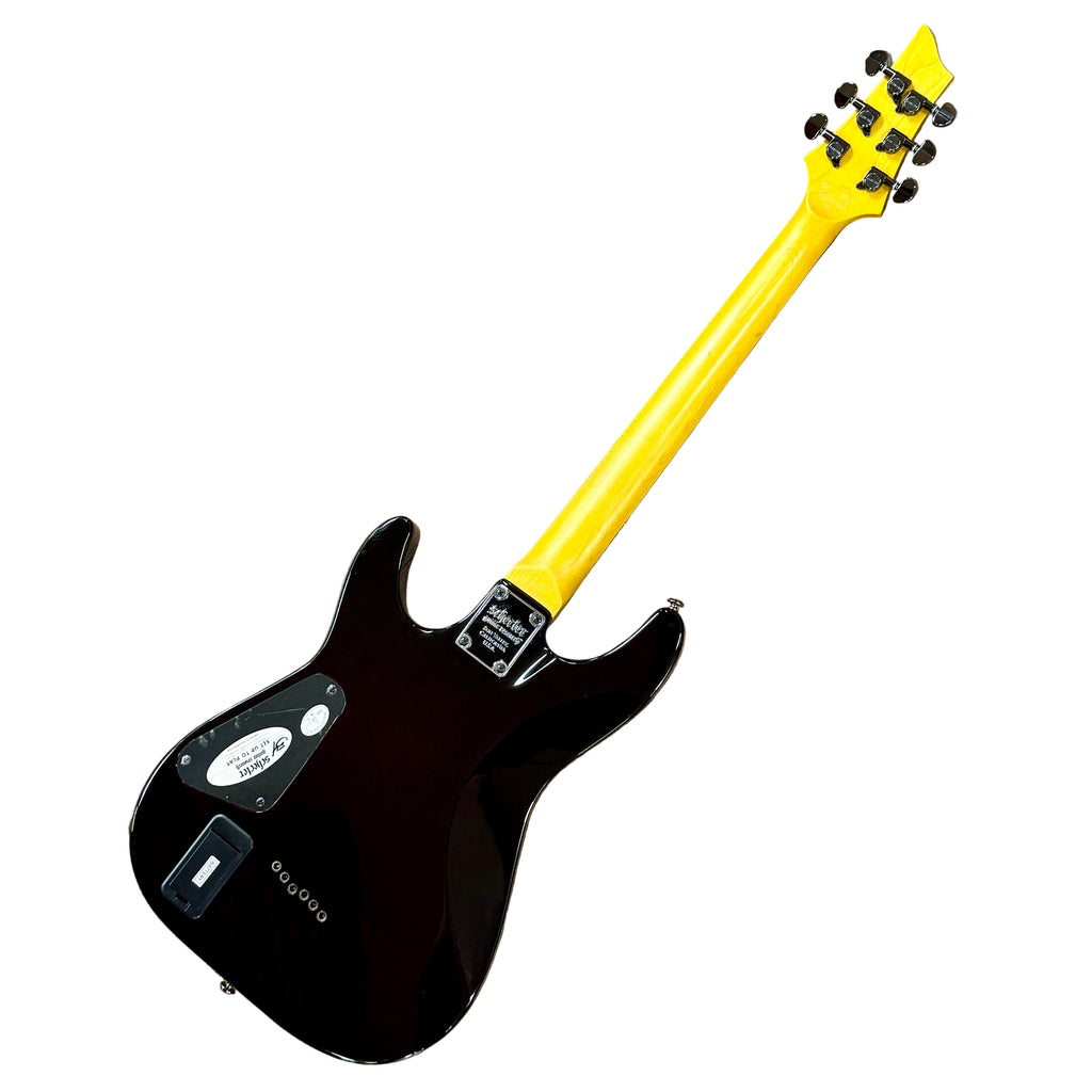 Schecter Diamond Series DEMON-6 Electric Guitar Black electric guitar with a yellow neck on a wooden floor