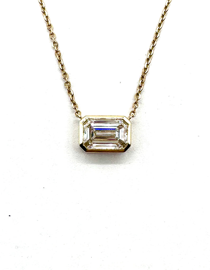 Diamond necklace with emerald-cut pendant on a white background