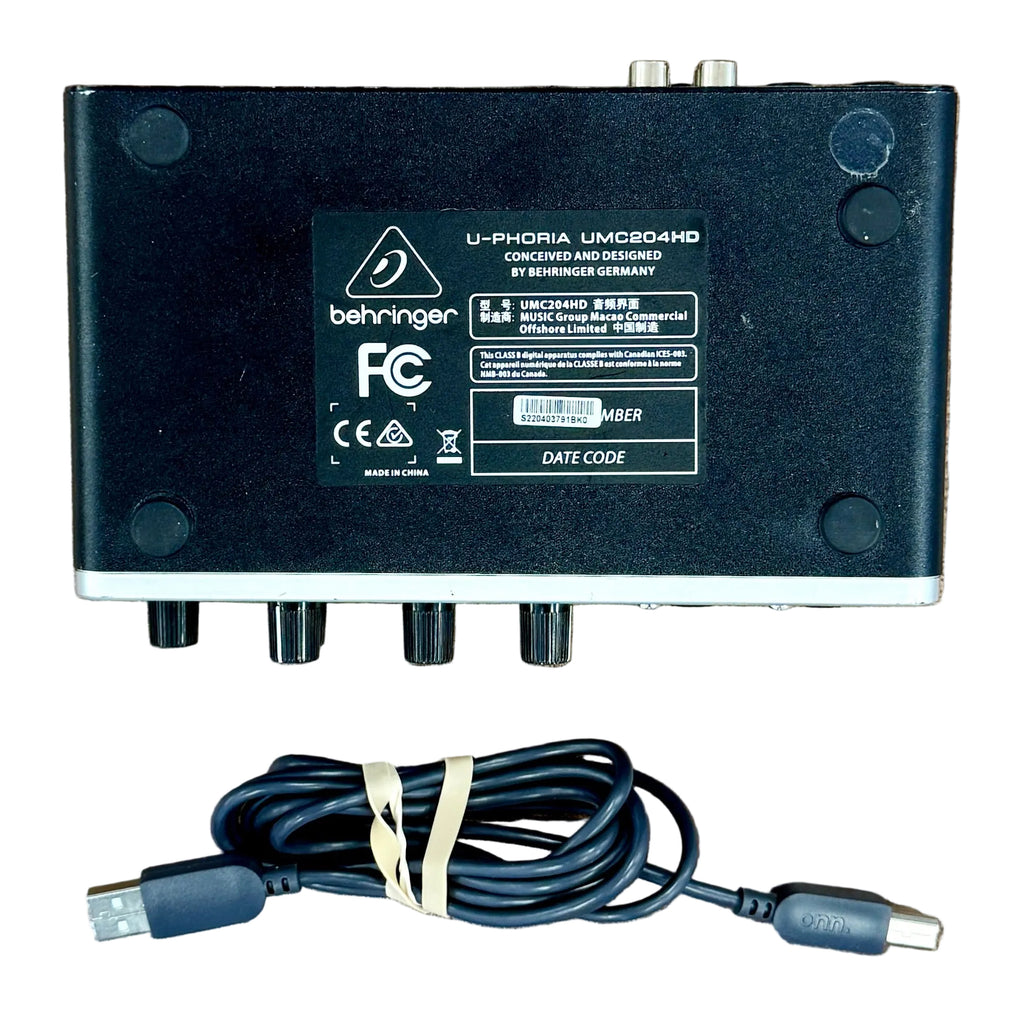 Behringer U-PHORIA UMC204HD USB Audio Interface Black electronic device with a cable on a wooden surface