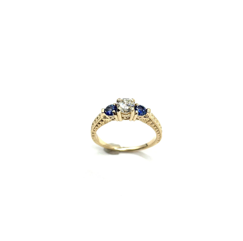 Gold ring with blue gemstones and a diamond on a white background