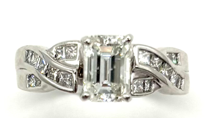 Diamond ring with a central emerald-cut diamond and smaller diamonds on a white background