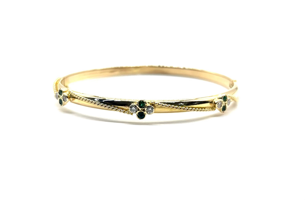 Gold bracelet with green gemstones on a white background