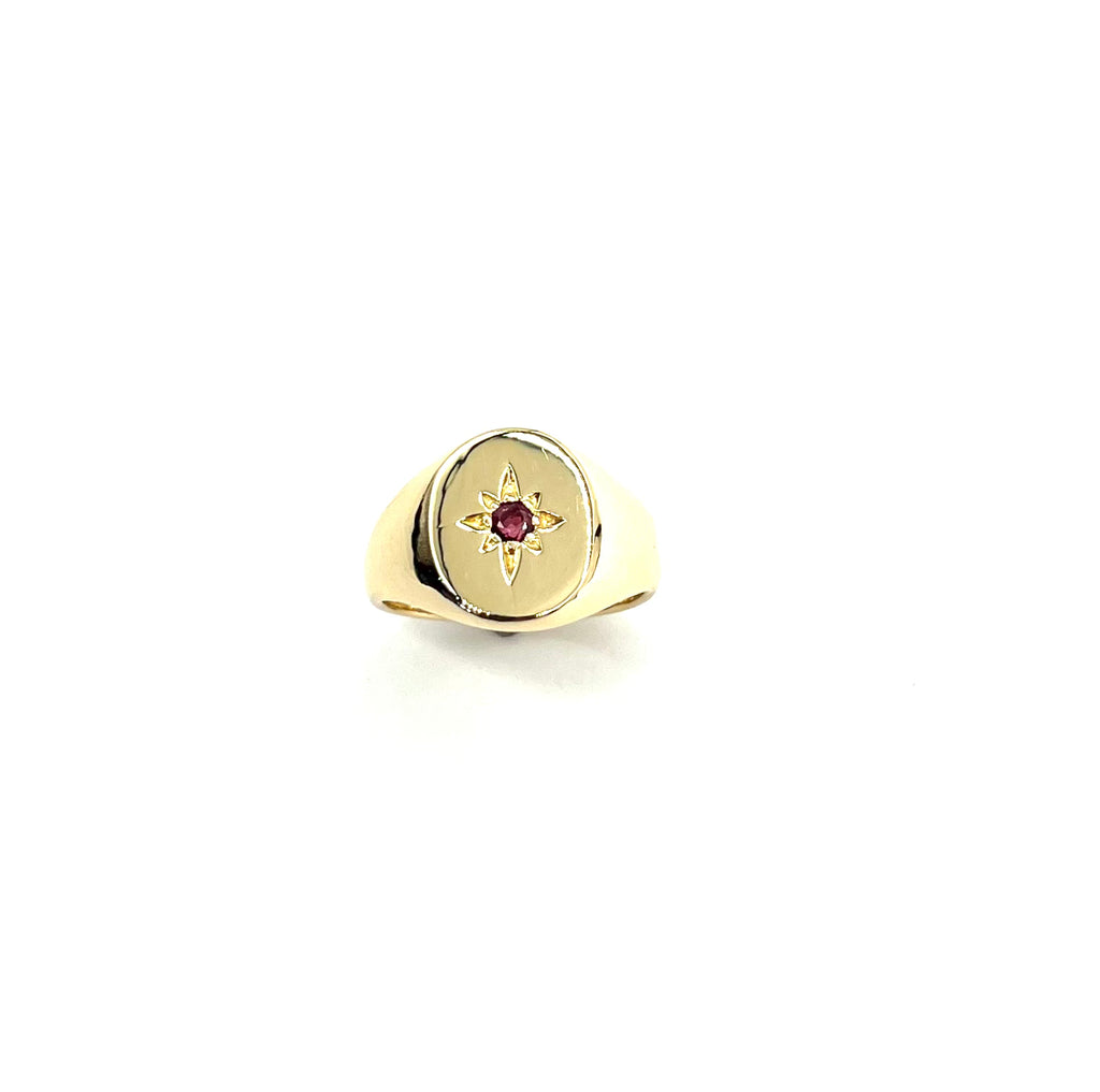 Gold ring with a red gemstone on a white background