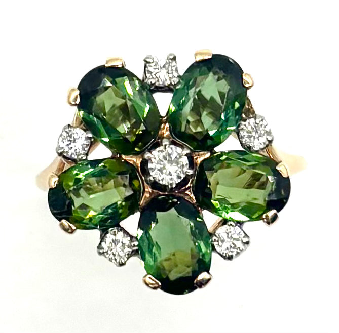 Gold ring with green gemstones and diamonds on a white background