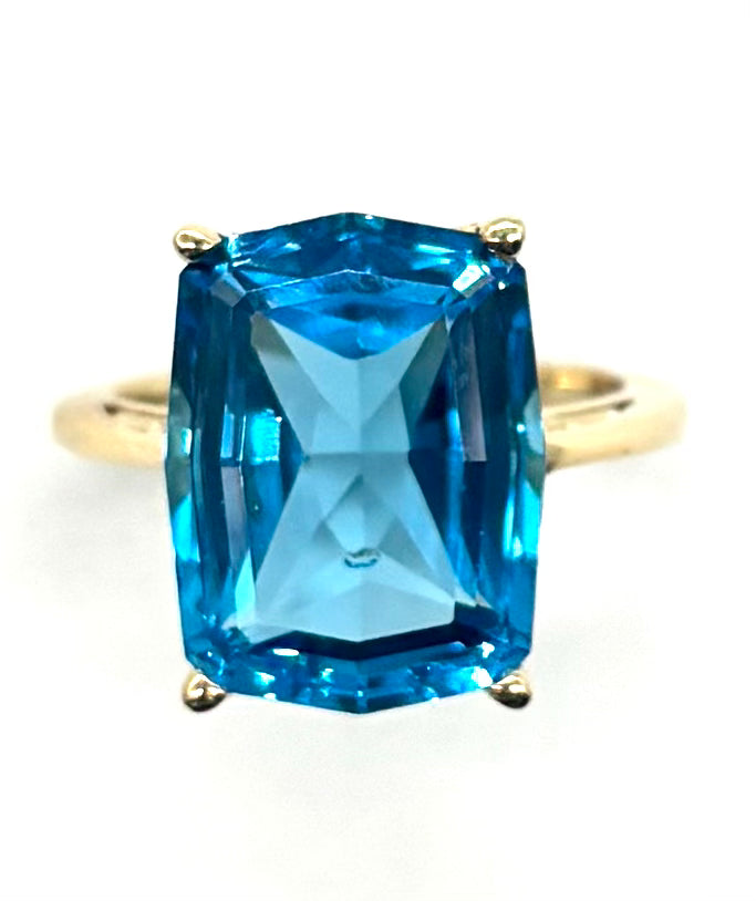 Gold ring with a large blue gemstone on a white background