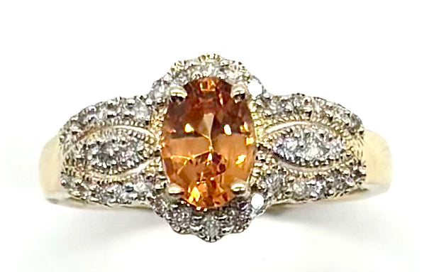 Gold ring with a large orange gemstone and smaller diamonds on a white background