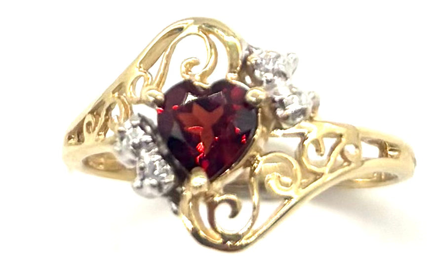 Gold ring with a heart-shaped red gemstone and smaller clear stones on a white background