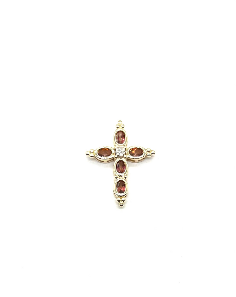 Gold cross pendant with embedded gemstones on a white background