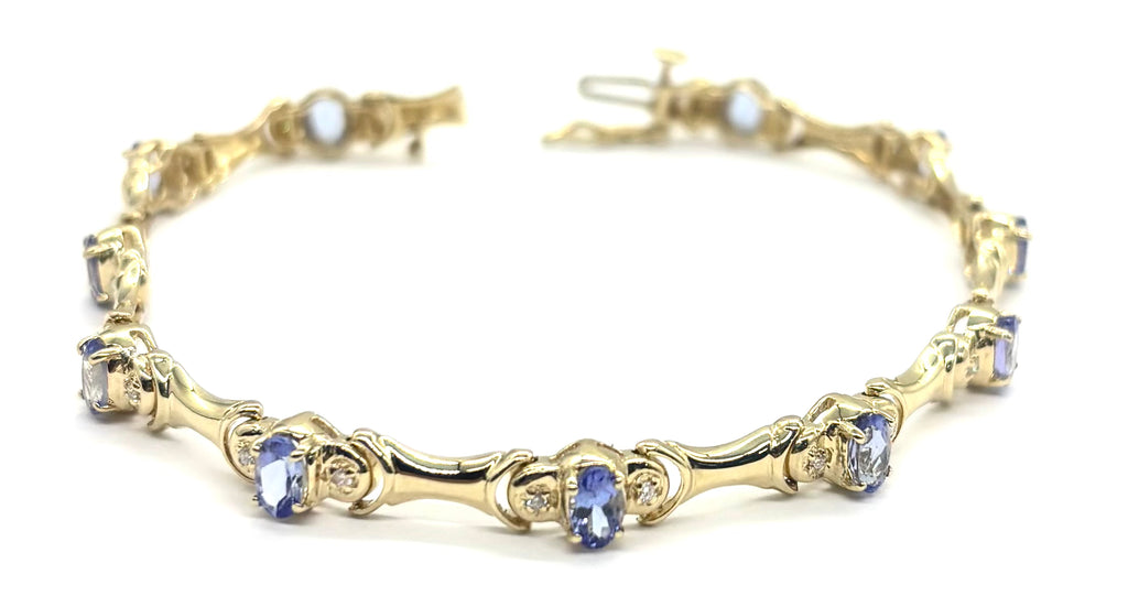 Gold bracelet with blue gemstones on a white background