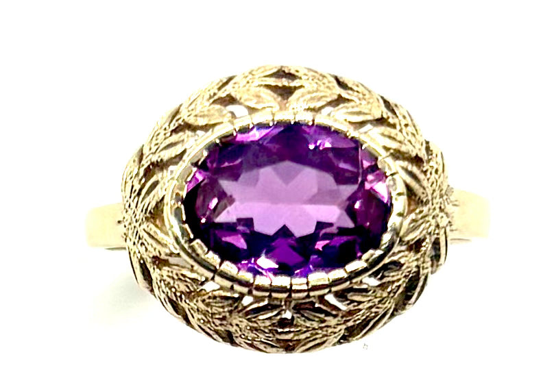Gold ring with a purple gemstone on a white background