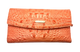 Orange textured clutch bag with a brand logo on a white background