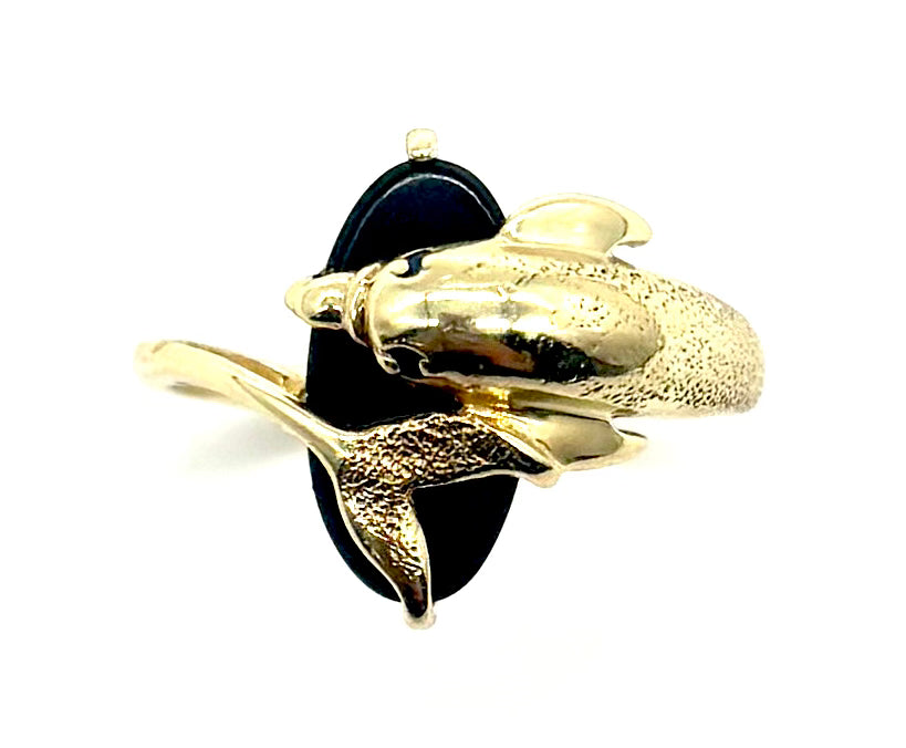 Gold dolphin brooch with black enamel on a white background