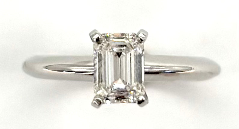 Diamond ring with emerald-cut gemstone on a white background