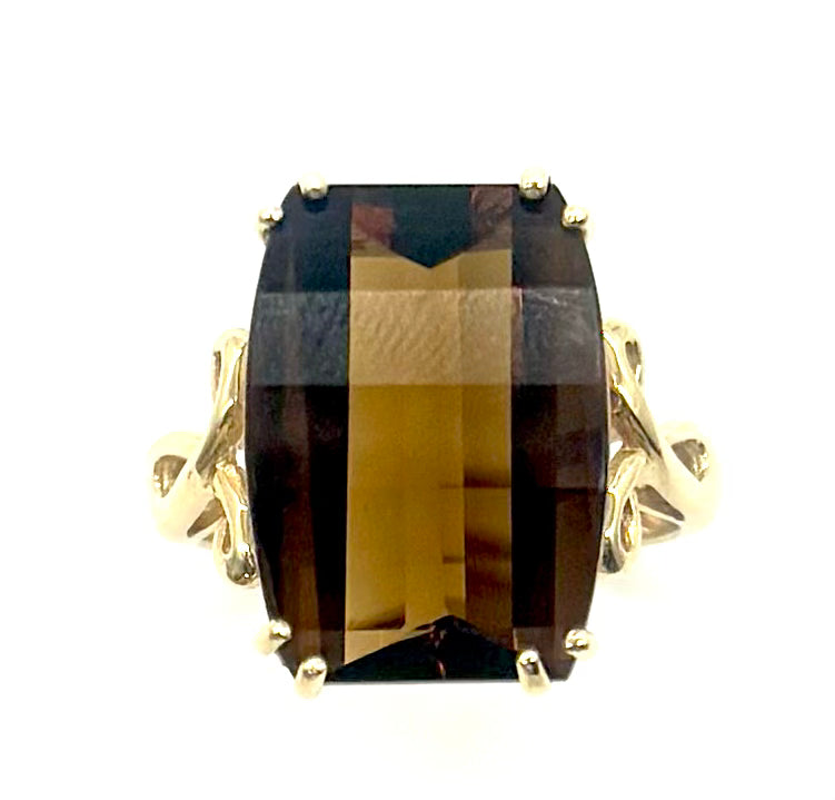 Gold ring with a large brown gemstone on a white background