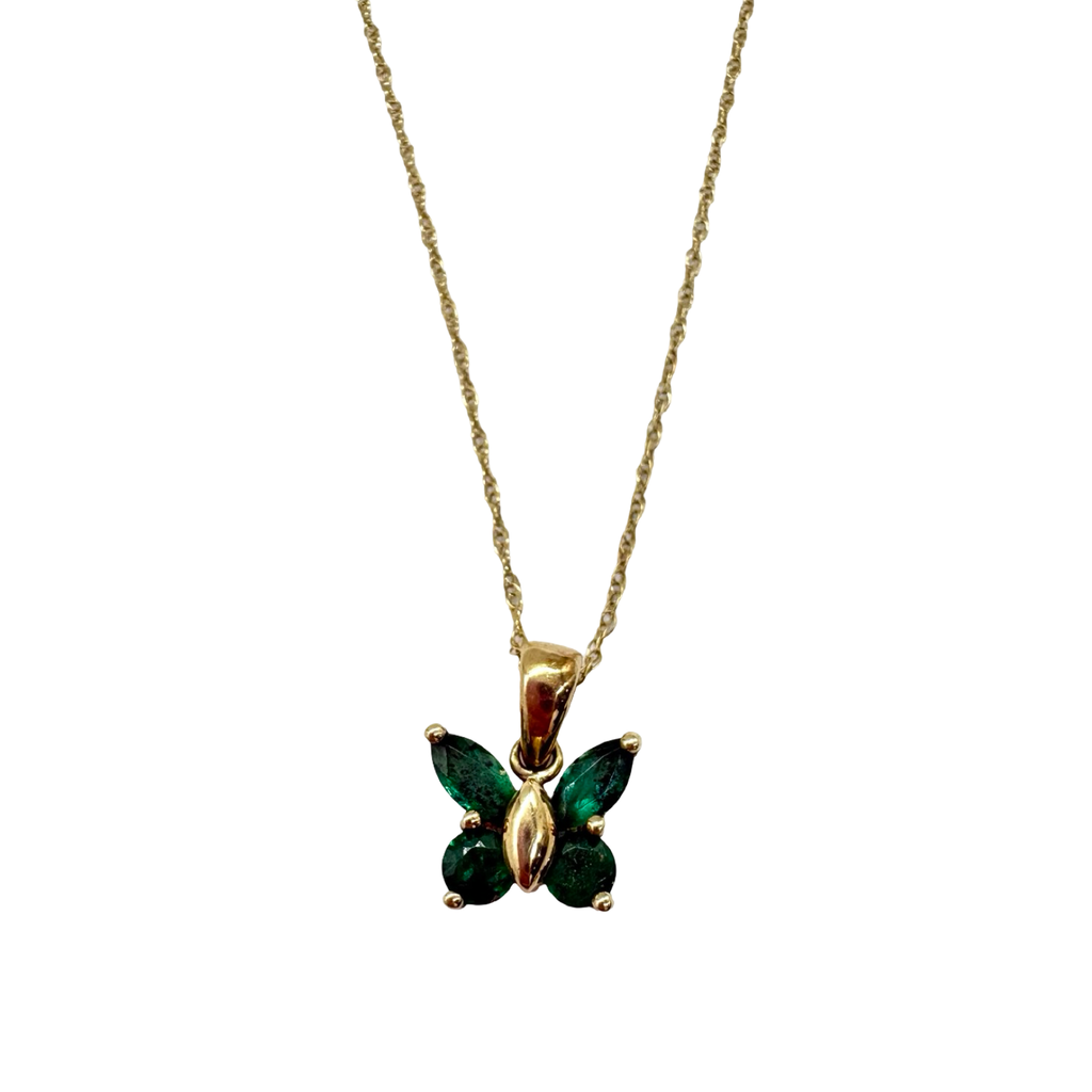 Gold butterfly pendant with green gemstones on a chain against a white background