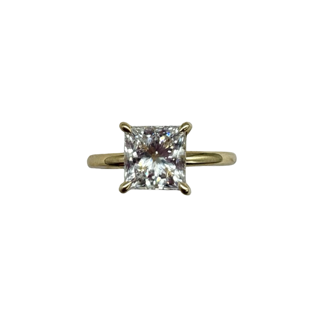 Gold ring with a square-cut diamond on a white background