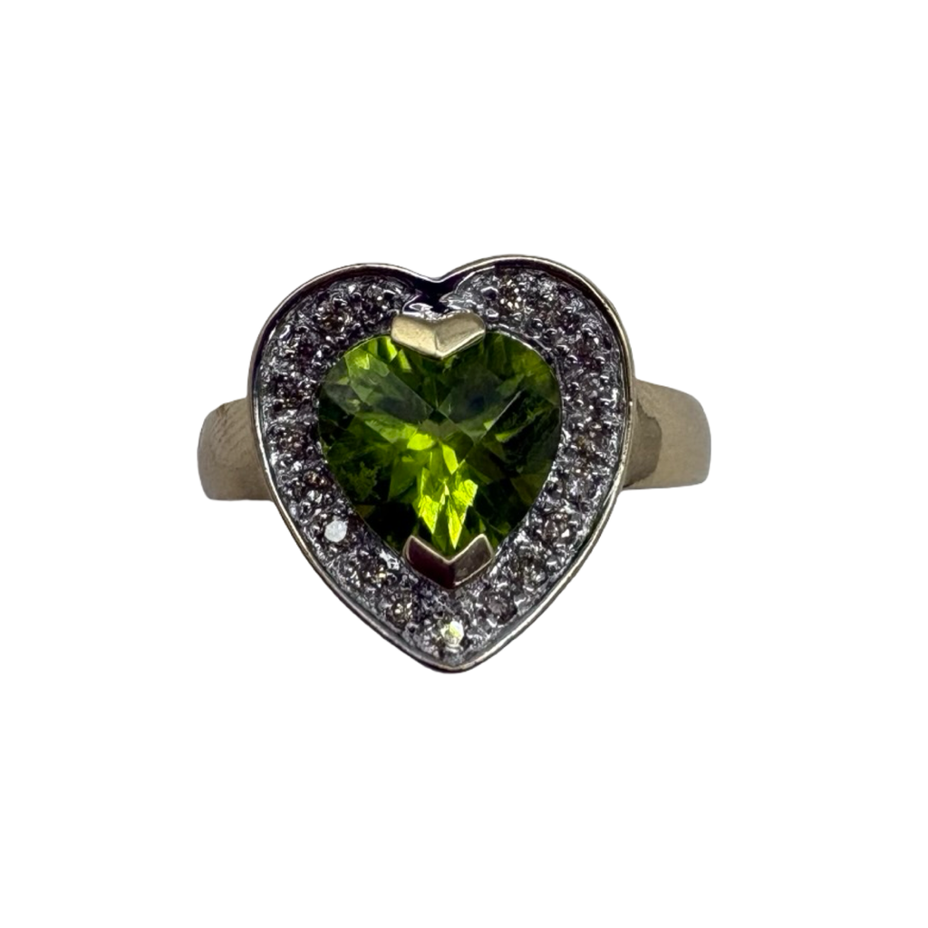 Heart-shaped ring with green gemstone and diamond accents on a white background