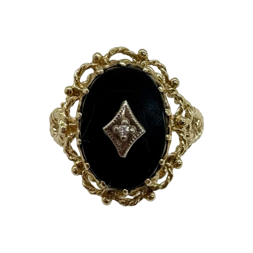 Gold ring with a black stone and diamond-shaped center on a white background