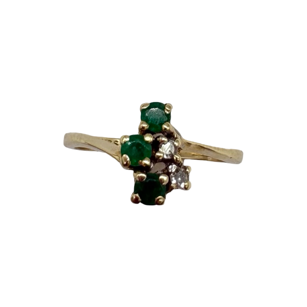 Gold ring with green gemstones on a white background