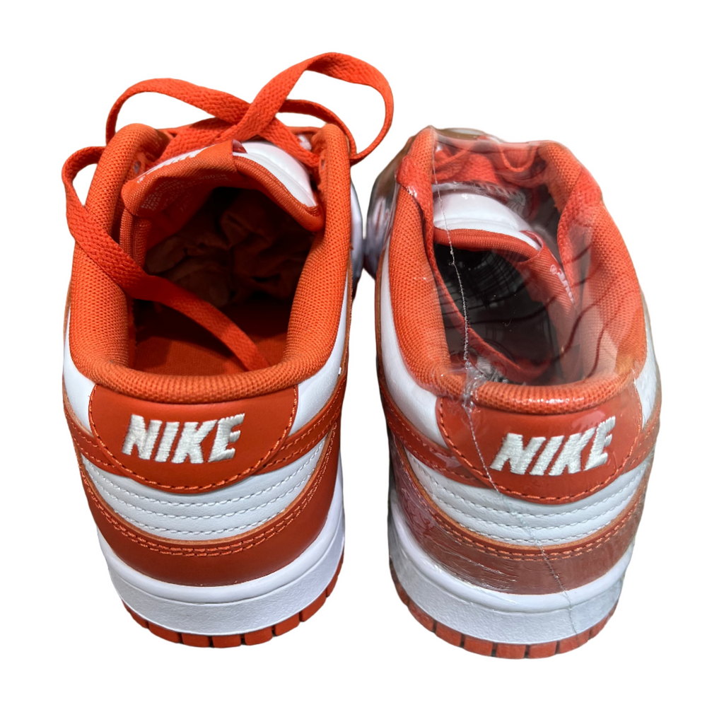 Orange and white Nike sneakers on a concrete surface