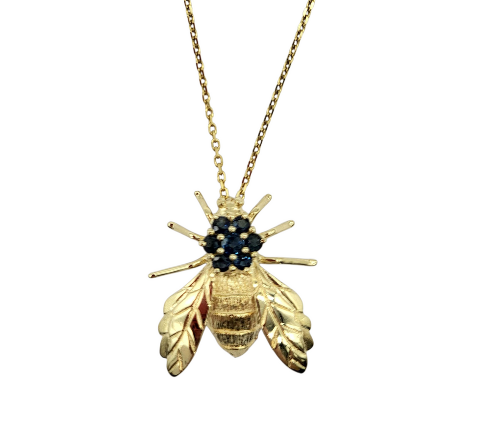 Gold bee-shaped pendant necklace with gemstones on a white background