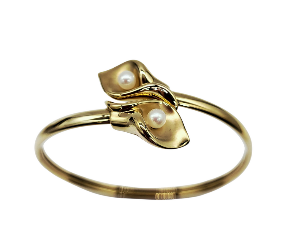 Gold ring with leaf design and pearls on a white background