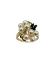 Pearl ring with gold band and black gemstone on a white background