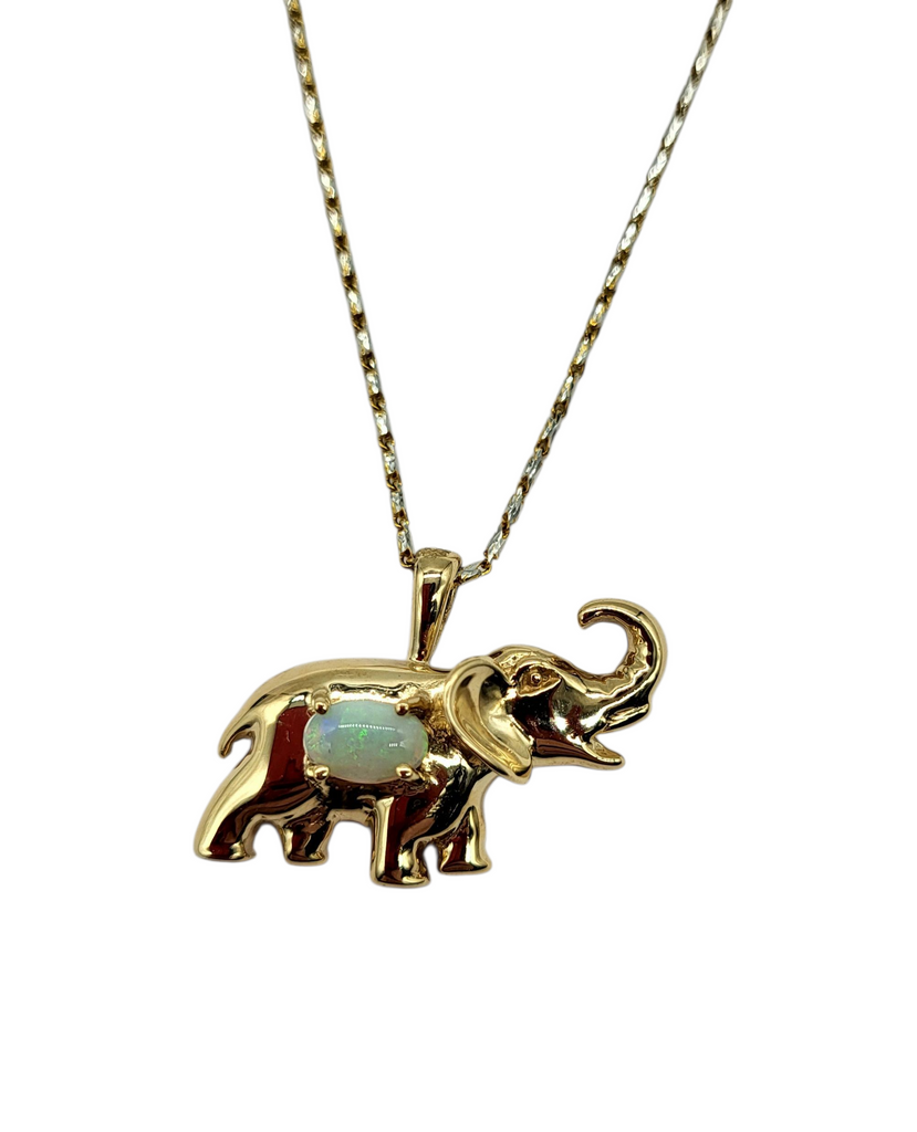 Gold elephant pendant with opal stone on a chain against a white background