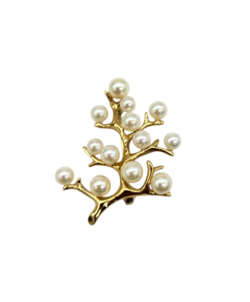 Gold brooch with pearl-like beads on a white background